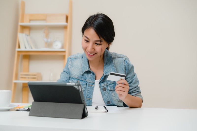 beautiful smart business asian woman using tablet buying online shopping by credit card while wear smart casual sitting 